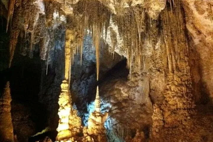 All'interno di una grotta con grandi stalattiti che pendono dal soffitto e stalagmiti sul pavimento.