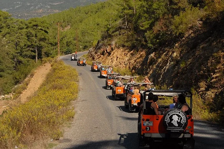 Ein Konvoi aus orangefarbenen offenen Jeeps auf einer kurvenreichen Bergstraße.